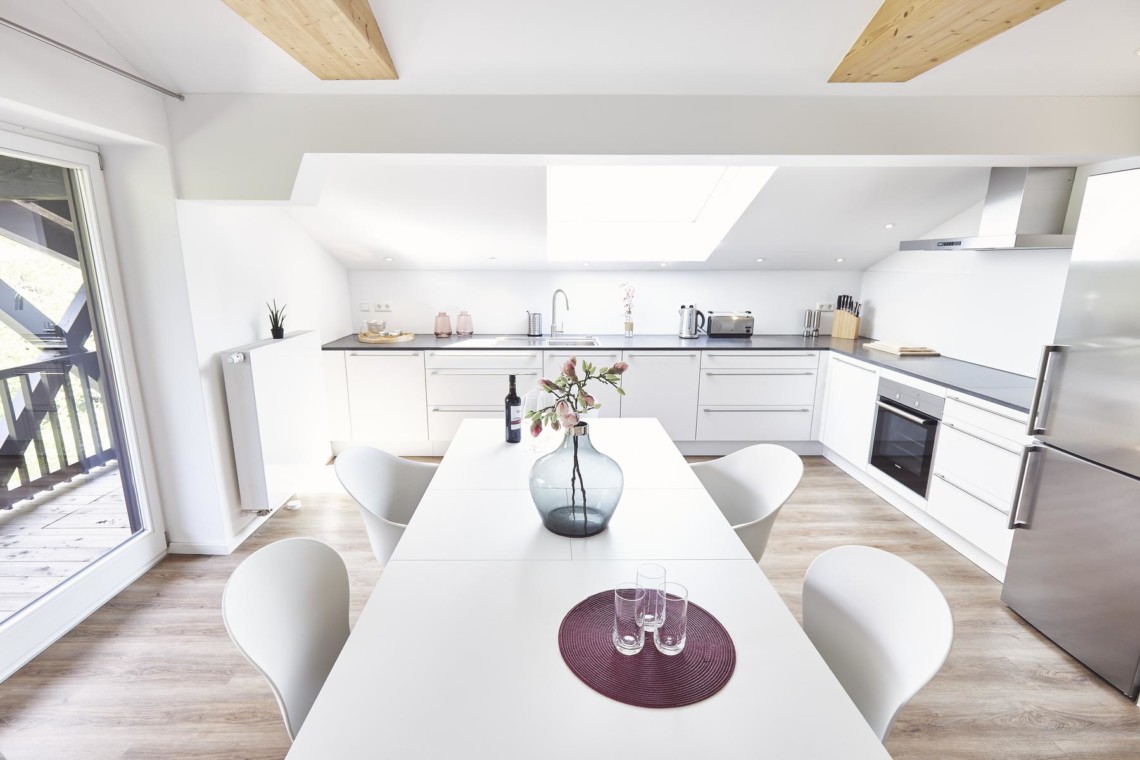 Moderne Ferienwohnung mit eleganter Küche, Essbereich und Balkon in Bad Wiessee. Ideal für einen luxuriösen Aufenthalt.