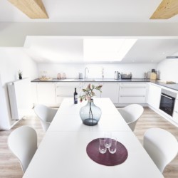 Moderne Ferienwohnung mit eleganter Küche, Essbereich und Balkon in Bad Wiessee. Ideal für einen luxuriösen Aufenthalt.