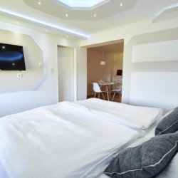 Gemütliches Zimmer in Bad Wiessee mit Doppelbett, TV und moderner Einrichtung. Ideal für Pärchen-Auszeit am Tegernsee!