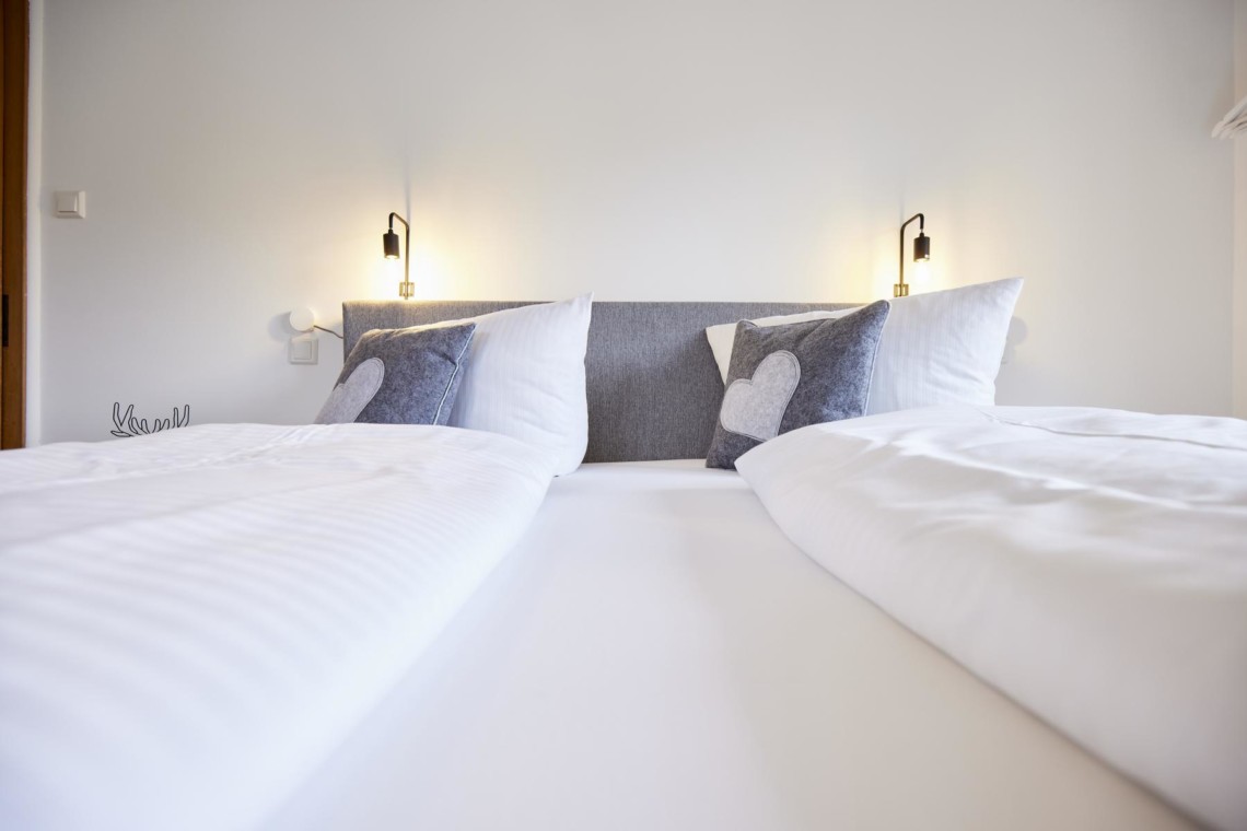 Gemütliches Doppelbett in heller, moderner Ferienwohnung in Bad Wiessee. Ideal für Paare am Tegernsee.