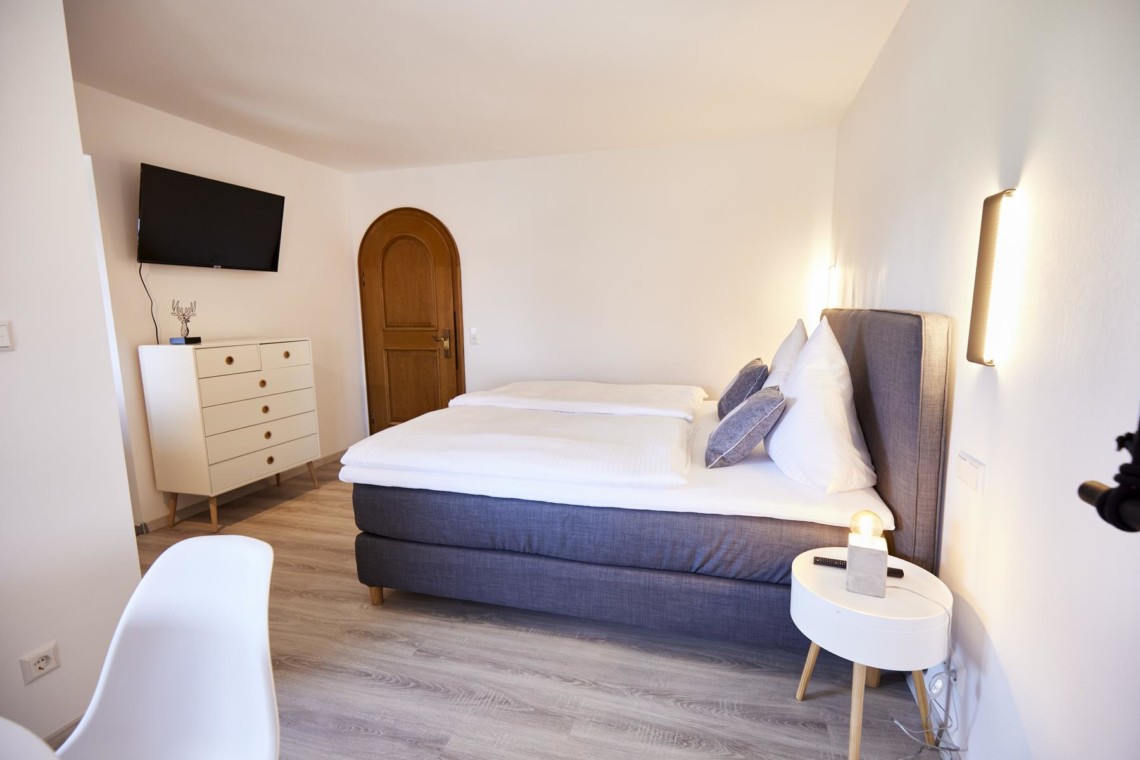 Gemütliches Schlafzimmer in einer Ferienwohnung in Bad Wiessee mit modernem Dekor und Flachbildfernseher.