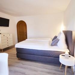 Gemütliches Schlafzimmer in einer Ferienwohnung in Bad Wiessee mit modernem Dekor und Flachbildfernseher.