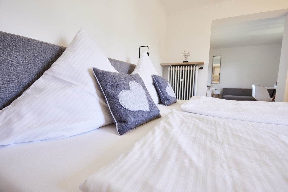 Gemütliches Doppelbett in stilvollem Zimmer am Tegernsee, ideal für Paare auf Urlaub in Bad Wiessee.