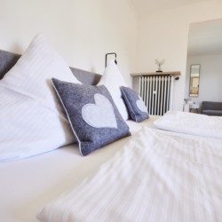 Gemütliches Doppelbett in stilvollem Zimmer am Tegernsee, ideal für Paare auf Urlaub in Bad Wiessee.