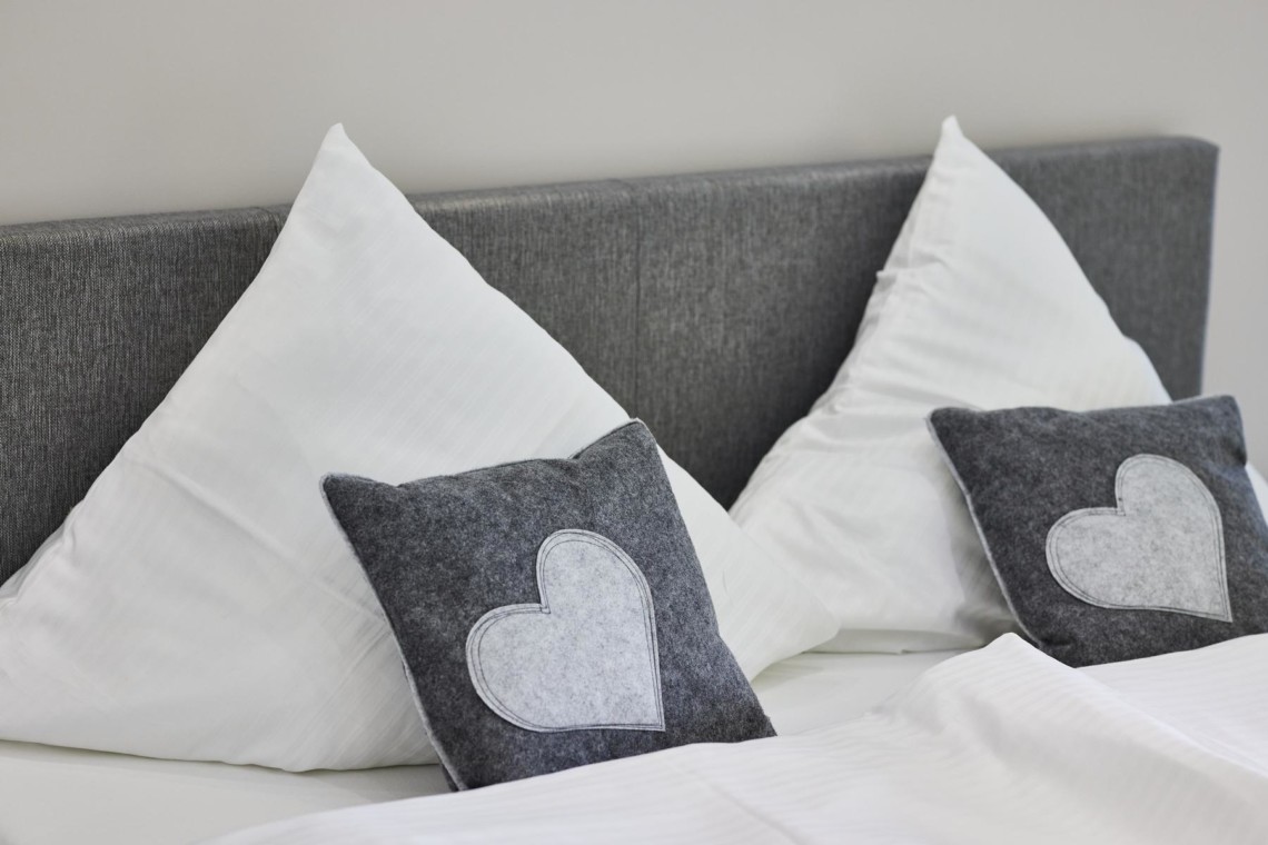 Gemütliche Ferienwohnung Bad Wiessee: Bett mit stilvollen Kissen, ideal für eine Auszeit am Tegernsee.