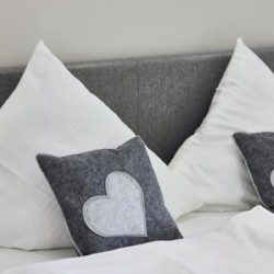 Gemütliche Ferienwohnung Bad Wiessee: Bett mit stilvollen Kissen, ideal für eine Auszeit am Tegernsee.