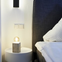 Elegantes Schlafzimmer in FeWo, Bad Wiessee. Gemütliche Einrichtung mit moderner Nachttischlampe.