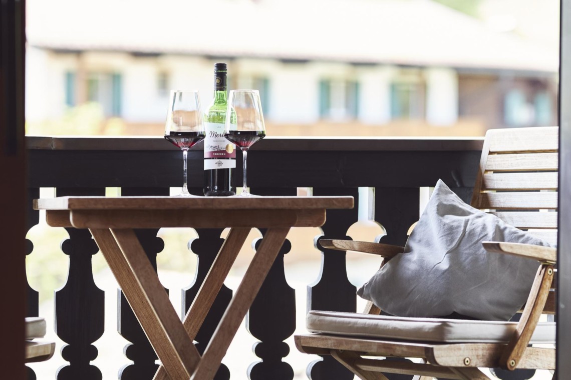 Gemütlicher Balkon mit Bergblick, Weingläsern und Sitzgelegenheiten – ideal für einen entspannten Aufenthalt in Bad Wiessee.