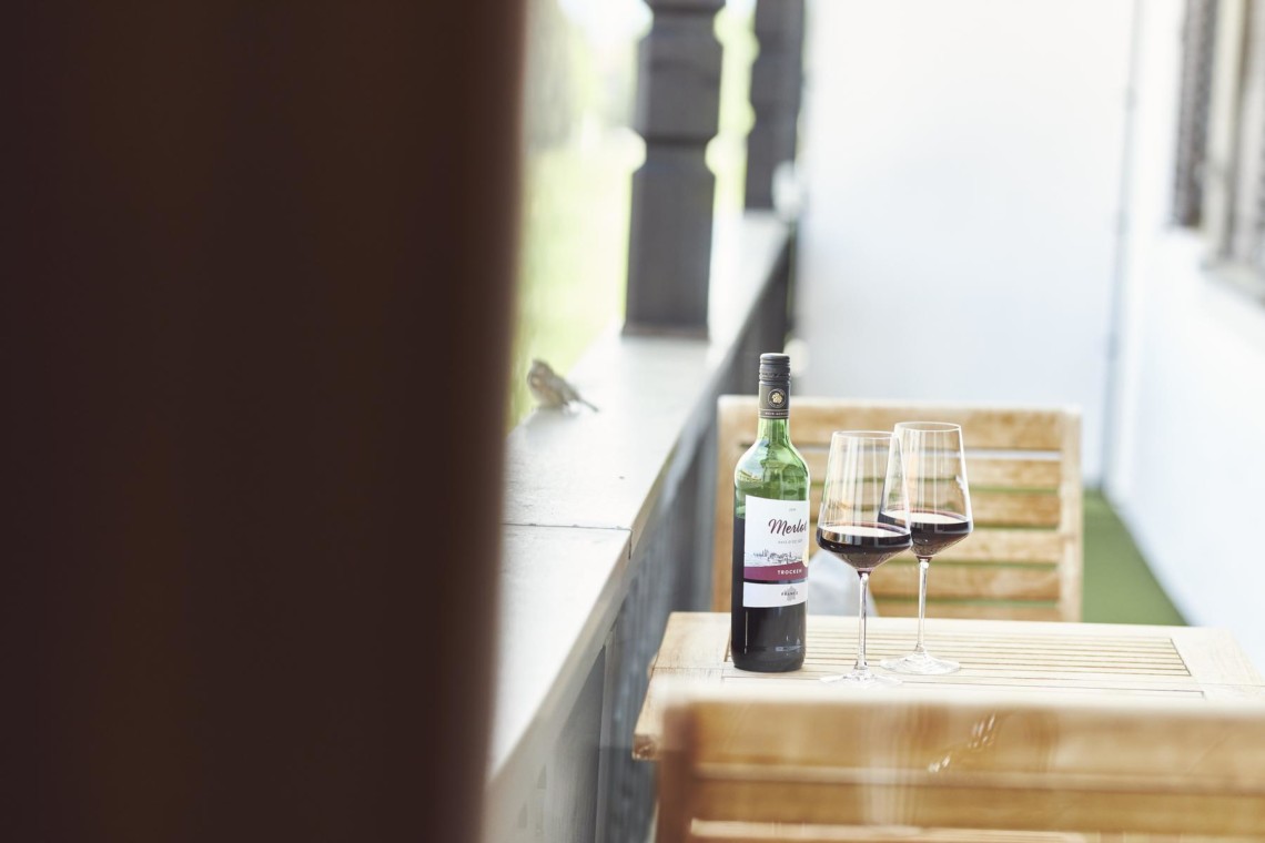 Gemütliches Balkon-Ambiente mit Weinflasche und Gläsern, perfekt für eine Auszeit in Bad Wiessee.