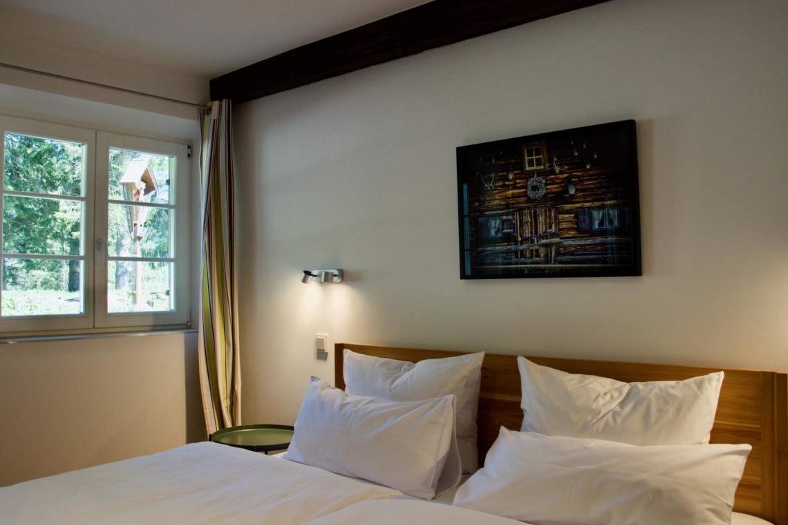 Gemütliches Doppelbett im hellen Zimmer mit Waldausblick nahe Schliersee-Spitzingsee – ideal für Paare.