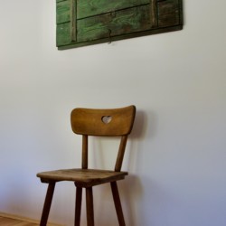 Helle, minimalistische Ferienwohnungseinrichtung mit Holzstuhl & Wanddekor in Schliersee-Spitzingsee. Ideal für Ruhesuchende.