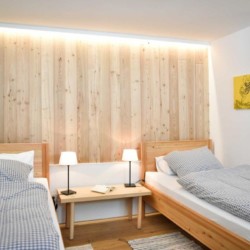 Gemütliches Zimmer im Stil von Schliersee-Spitzingsee mit Holzwand, hellen Betten und moderner Einrichtung. Ideal für Urlauber.