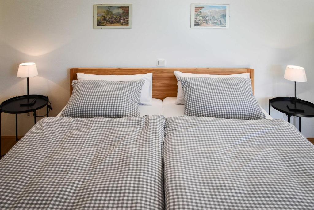 Gemütliches Schlafzimmer in Schliersee-Spitzingsee Ferienwohnung mit karierten Bettbezügen, Holzkopfteil und stimmungsvoller Beleuchtung.