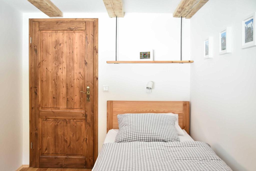 Gemütliches Schlafzimmer in Schliersee-Spitzingsee Ferienwohnung mit Holztür und kariertem Bett.