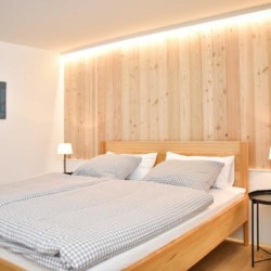 Gemütliches Schlafzimmer in Schliersee-Spitzingsee Ferienwohnung mit Holzpaneele und einladendem Doppelbett.