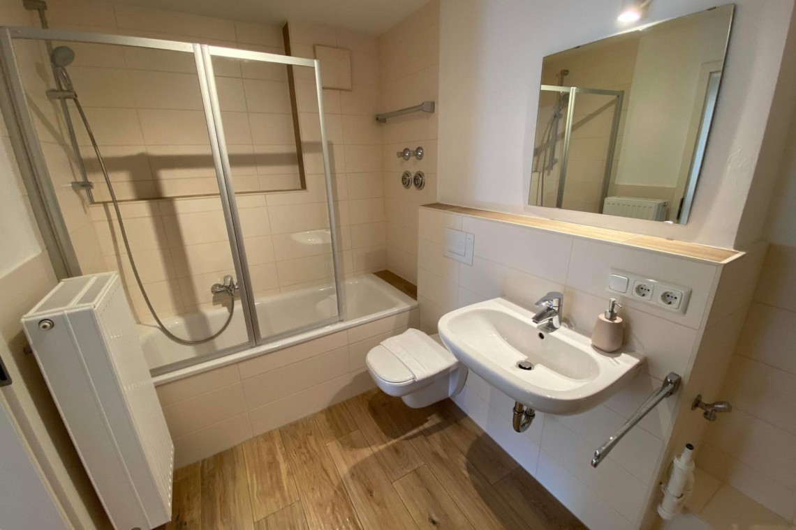 Modernes Badezimmer in Hausham Ferienwohnung, sauberes Design, Duschbadewanne, ideal für Erholungsurlaub.