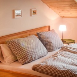 Gemütliches Schlafzimmer in Schliersee-Spitzingsee Ferienwohnung mit Holzdekor und Karo-Bettwäsche.