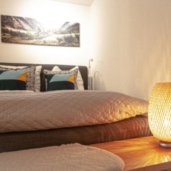 Gemütliches Schlafzimmer in einer Ferienwohnung in Rottach-Egern mit stilvoller Deko und warmem Licht.