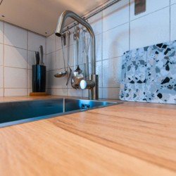 Moderne Ferienwohnung in Rottach-Egern, Holzarbeitsplatte, stilvolle Kücheneinrichtung, perfekt für Erholung in den Alpen.