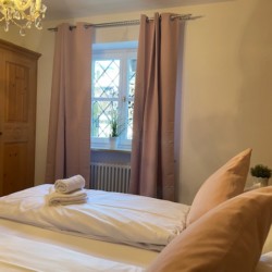 Gemütliches Schlafzimmer in Schliersee Ferienwohnung mit holzgetäfelten Wänden und elegantem Kronleuchter.