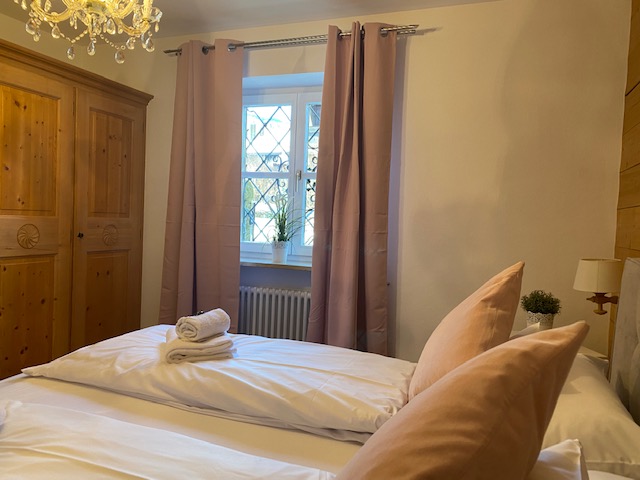 Gemütliches Schlafzimmer in Schliersee Ferienwohnung mit holzgetäfelten Wänden und elegantem Kronleuchter.