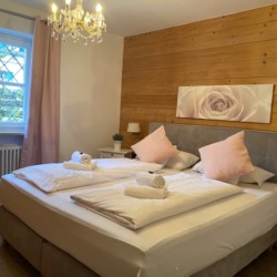 Gemütliches Schlafzimmer der Ferienwohnung "Wendelstein" in Schliersee, mit Doppelbett und Holzwand.