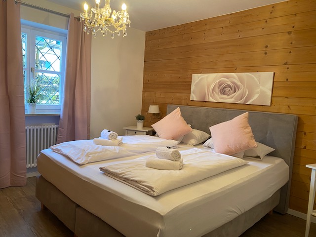 Gemütliches Schlafzimmer der Ferienwohnung "Wendelstein" in Schliersee, mit Doppelbett und Holzwand.