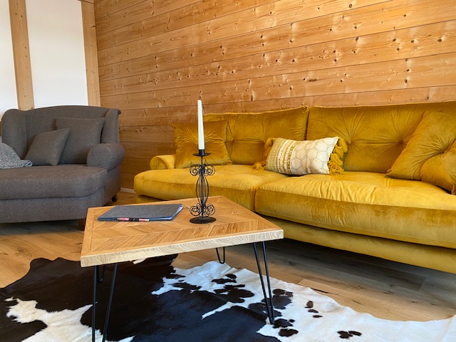 Gemütliche Fewo in Schliersee: stylisches Wohnzimmer mit Holzwand und gelbem Sofa. Ideal für Entspannung! #SchlierseeUnterkunft