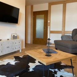 Gemütliches Wohnzimmer mit Sofa, TV und Holzdekor in Schliersee Ferienwohnung. Ideal für Entspannung.