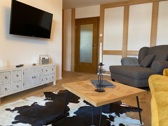 Gemütliches Wohnzimmer mit Sofa, TV und Holzdekor in Schliersee Ferienwohnung. Ideal für Entspannung.