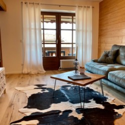 Gemütliches Wohnzimmer der Ferienwohnung "Brecherspitz" in Schliersee mit Sofa und Holzakzenten. Ideal für Urlaub.