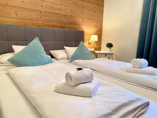 Gemütliches Schlafzimmer in der Ferienwohnung Brecherspitz in Schliersee mit modernen, einladenden Betten.