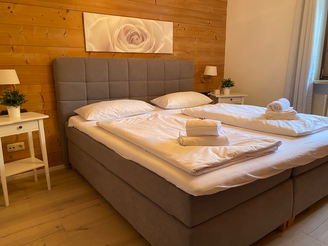 Gemütliches Schlafzimmer in Schlierseer Ferienwohnung "Taubenstein" mit Doppelbett, Holzwand & Kunst. Ideal für Erholung.