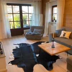 Gemütliches Wohnzimmer einer Ferienwohnung in Schliersee mit Sofa, Holztisch und Alpenflair. Ideal für Urlaubsaufenthalte.