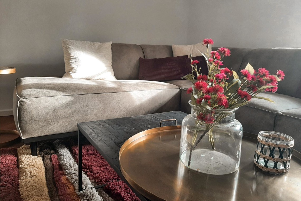 Gemütliches Wohnzimmer der Ferienwohnung "Geitau59 II" mit Sofa & Blumen, ideal für Geitau-Urlaub. Buchen auf stayfritz.com.