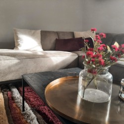 Gemütliches Wohnzimmer der Ferienwohnung "Geitau59 II" mit Sofa & Blumen, ideal für Geitau-Urlaub. Buchen auf stayfritz.com.
