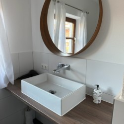 Modernes Bad in Ferienwohnung Taubenstein, Schliersee - stilvolles Ambiente mit Design-Waschbecken und Holzakzenten.