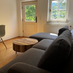 Gemütliches Wohnzimmer in Hausham, helle Ferienwohnung mit Holzfußboden und Blick ins Grüne. Ideal für Erholung.