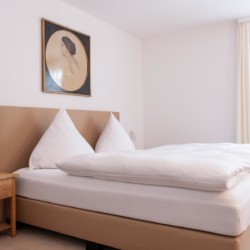 Helles Schlafzimmer in Bad Wiesseer Ferienwohnung mit komfortablem Bett und stilvollem Dekor. Ideal für Erholung!