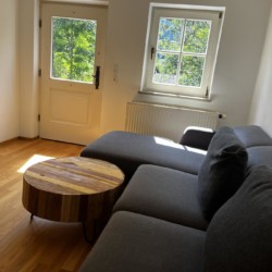 Gemütliche Ferienwohnung in Hausham mit hellem Wohnzimmer, modernem Sofa und Blick ins Grüne. Ideal für Erholungssuchende.