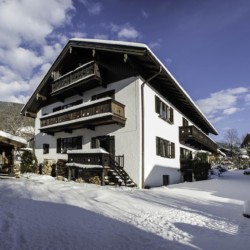Gemütliches bayrisches Ferienhaus im Schnee mit Balkonen, ideal für Tegernsee-Urlaub.