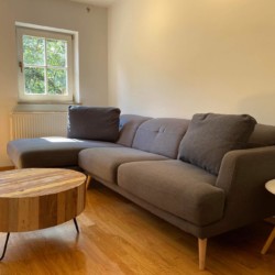 Gemütliche Ferienwohnung in Hausham mit moderner Couch und Holztisch, helle Räume, ideal für Erholung. #HaushamFerienwohnung