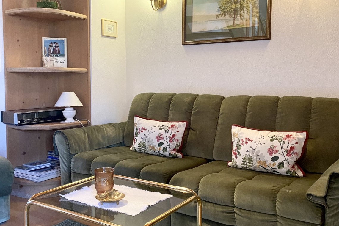 Gemütliches Wohnzimmer in Ferienwohnung mit grünem Sofa und Holzdetails in Bad Wiessee.