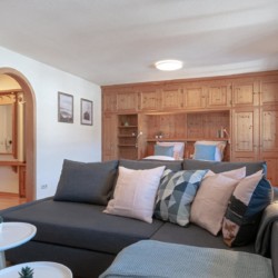 Gemütlich eingerichtetes Wohnzimmer einer Ferienwohnung in Bad Wiessee mit Holzmöbeln und Sofaecke.