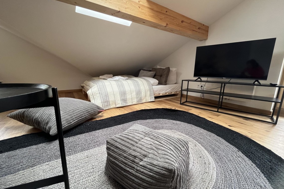 Gemütliches Dachgeschoss-Zimmer mit Holzbalken, TV und moderner Einrichtung in Bayrischzell.