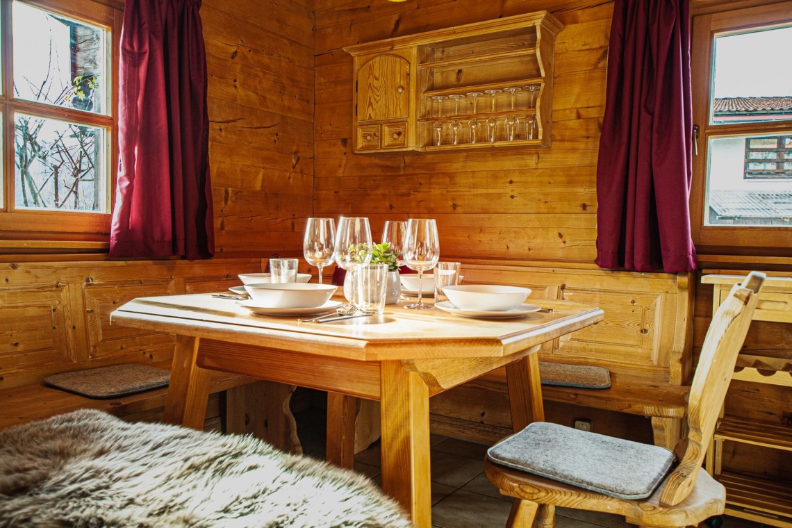 Gemütliches Esszimmer in Holzoptik, mit weinrot Vorhängen und Bergblick, ideal für Schliersee Urlaub.