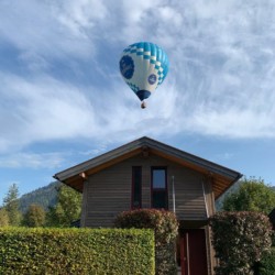 Gemütliches Ferienhaus in Schliersee-Neuhaus mit Heißluftballon im blauen Himmel. Ideal für eine idyllische Auszeit.