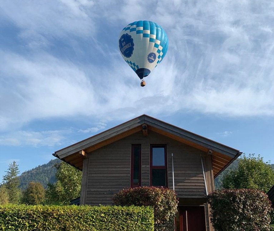 Gemütliches Ferienhaus in Schliersee-Neuhaus mit Heißluftballon im blauen Himmel. Ideal für eine idyllische Auszeit.