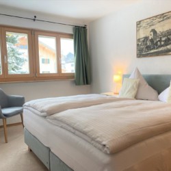 Gemütliches Schlafzimmer in Bad Wiesseer FeWo mit Balkon, helle Einrichtung und Bergblick. Ideal für Erholung!