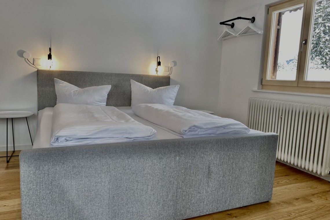 Gemütliches Schlafzimmer in Bad Wiessee Ferienwohnung mit bequemen Betten, moderner Beleuchtung und stilvollem Dekor, ideal für Entspannung.